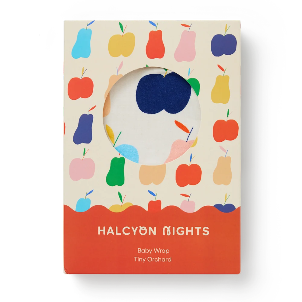 The product packaging for the 'Baby Wrap' by Tiny Orchard, featuring a cream-colored box decorated with a colorful pattern of stylized fruits (apples and pears) and a solid coral-orange bottom band with white text.