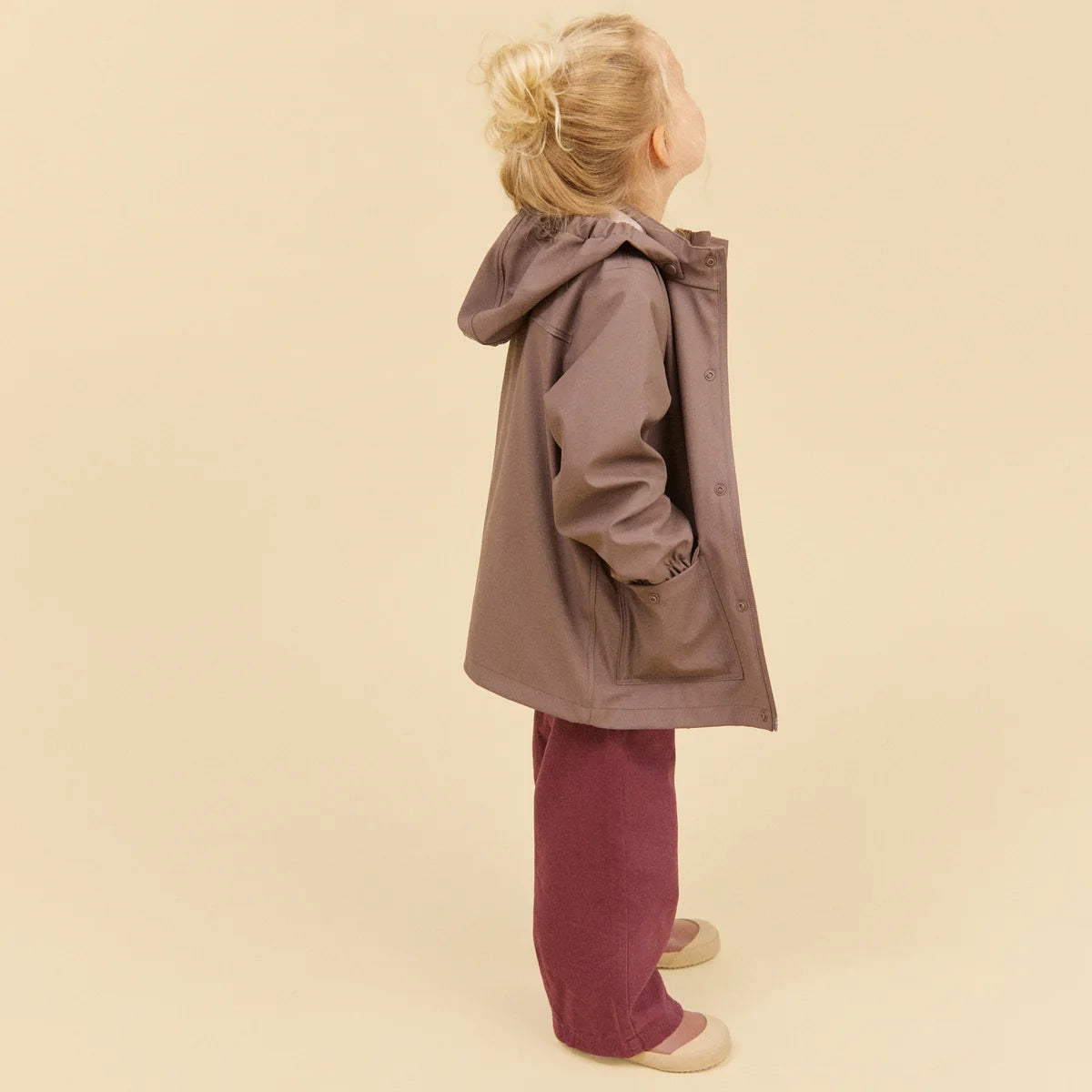 Child wearing a brown coat and pants on a beige background