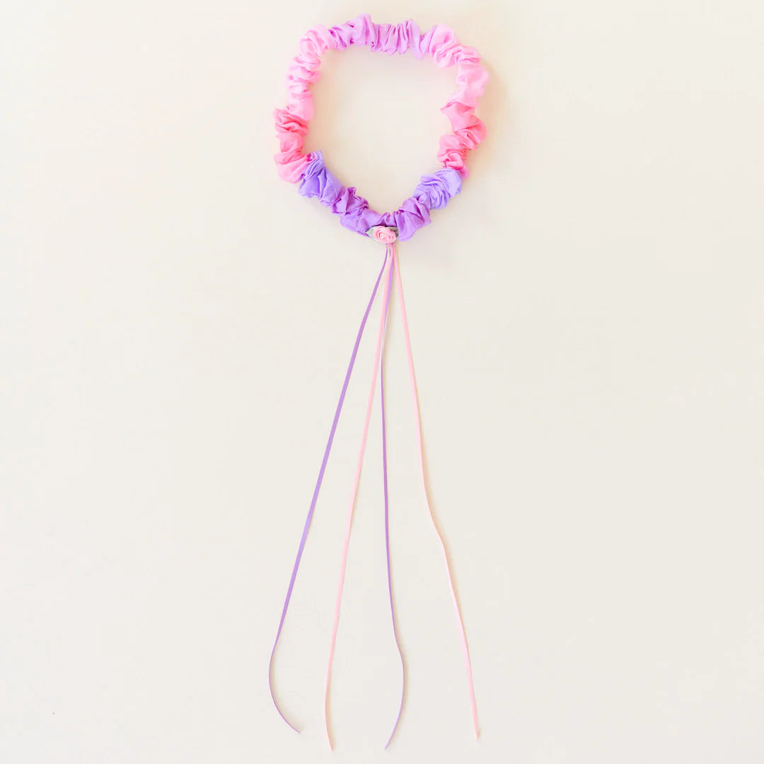 Pastel-colored hair garland with flower-shaped end on a light pink background