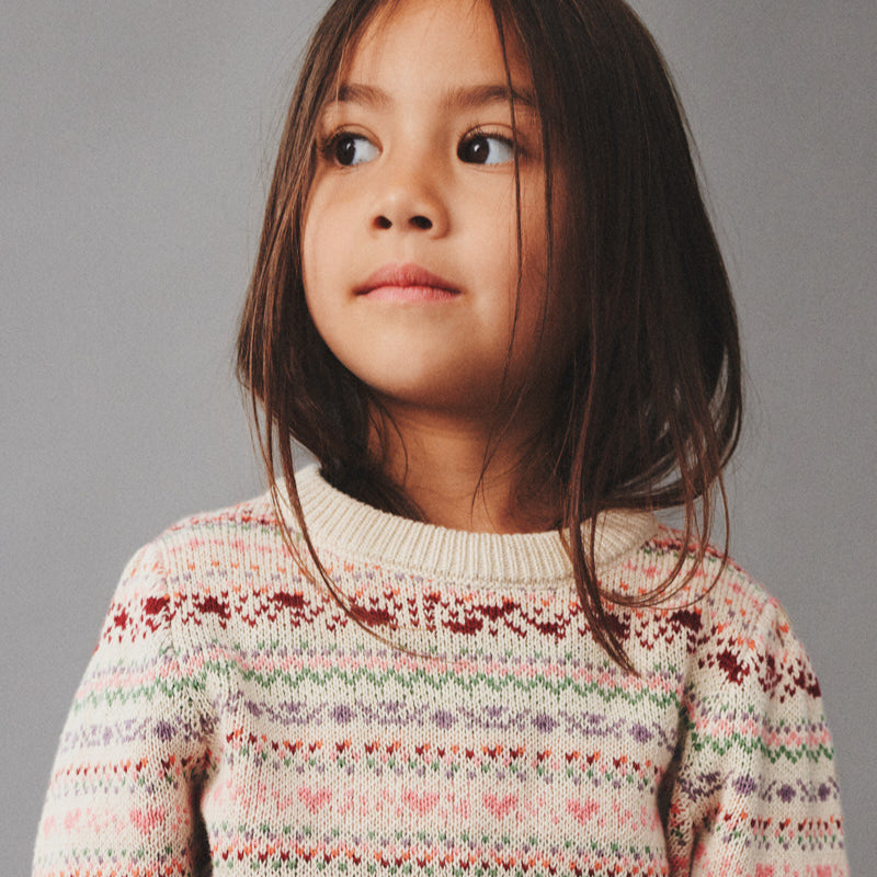 Child wearing patterned sweater on grey background
