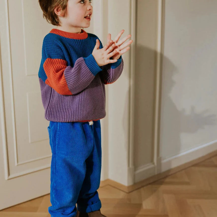 Child standing on a small platform indoors with wooden flooring and white walls.