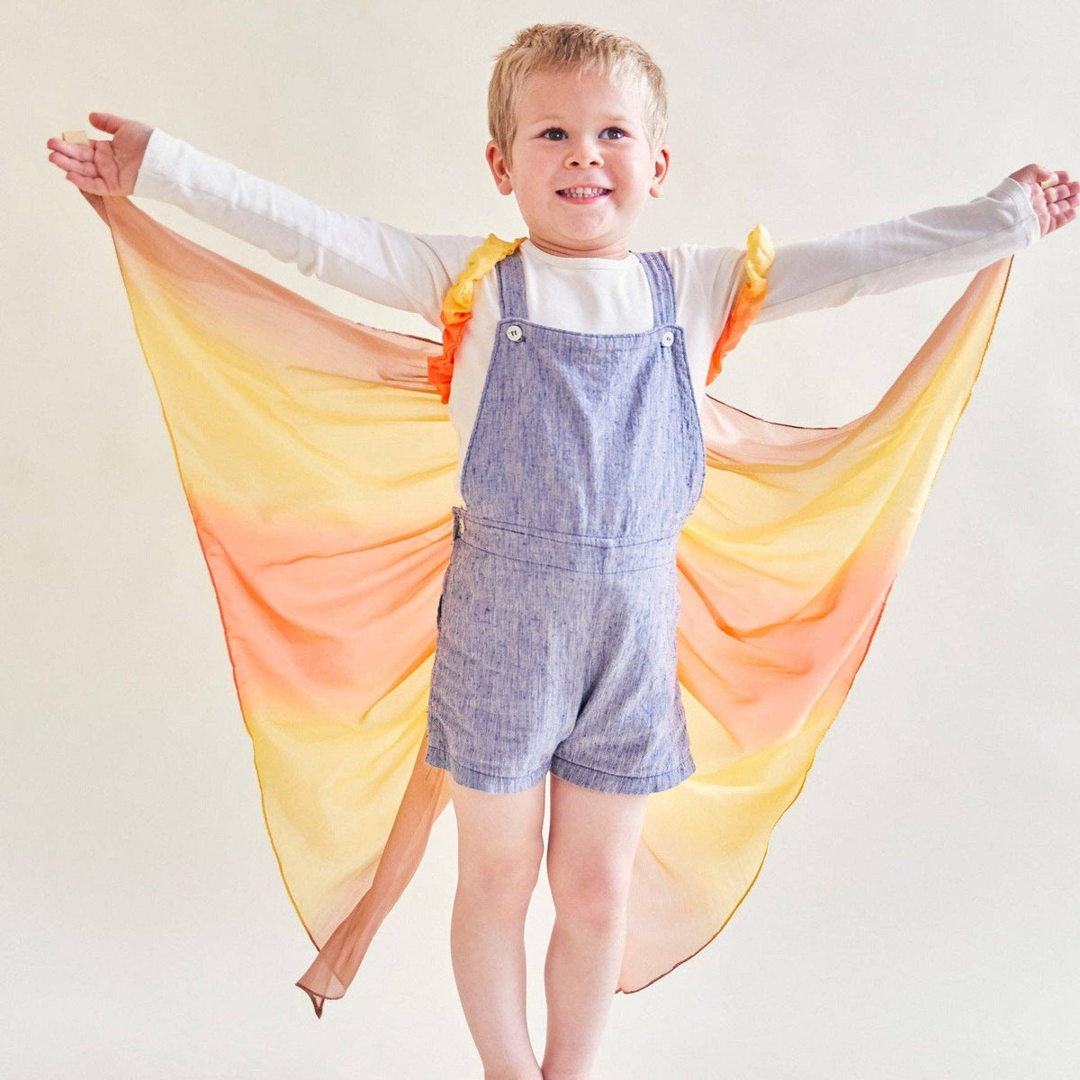 Child wearing a colorful wings with a plain background