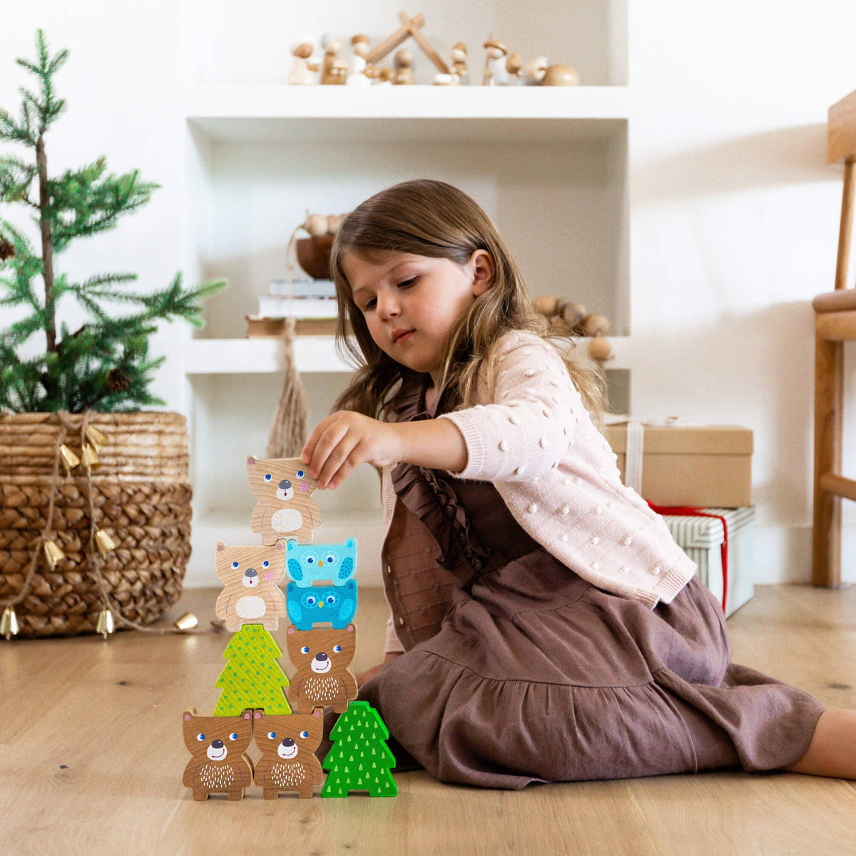 Child playing with wooden animal blocks on a wooden floor.