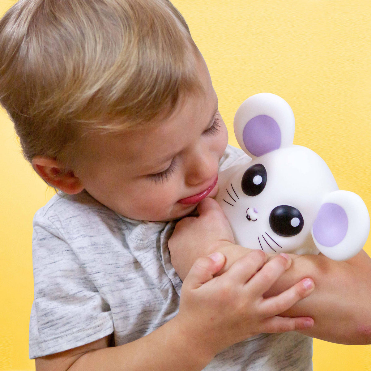 Child holding a plush toy against a yellow background