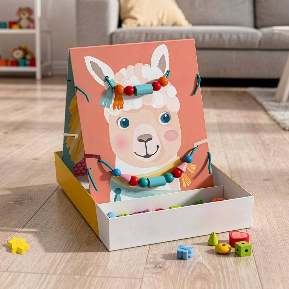 A children's wooden toy box featuring a colorful alpaca illustration on the front panel, shown open on a light wood floor in a living room setting. The box contains small wooden toy pieces, and several pieces are scattered nearby.