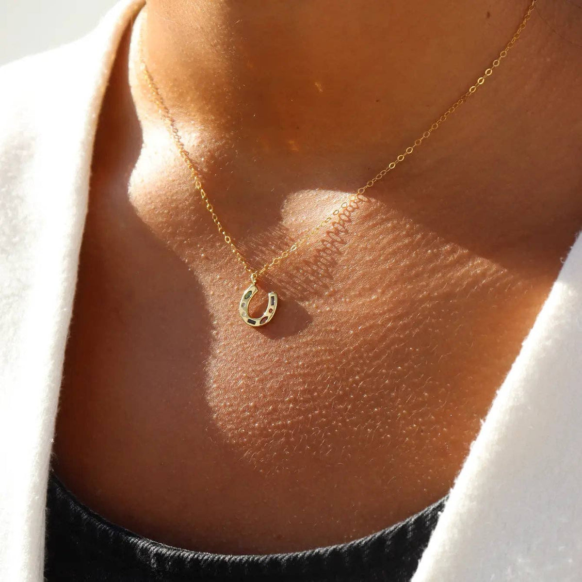 Gold necklace with a small pendant on a person's neck