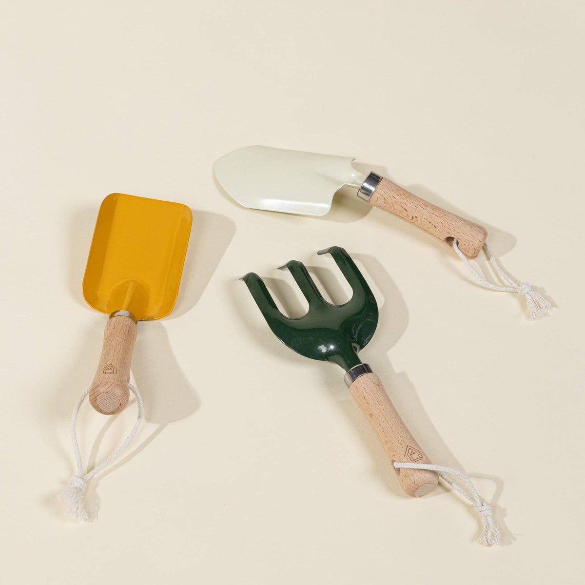 Set of three gardening tools with wooden handles on a beige background