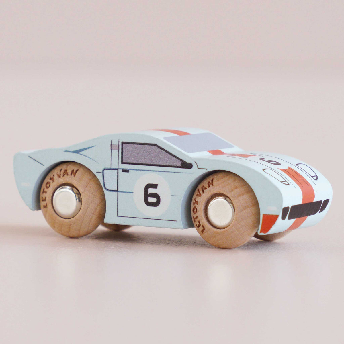 Wooden toy car with a light blue body, red and black accents, and the number 6 on a beige background.