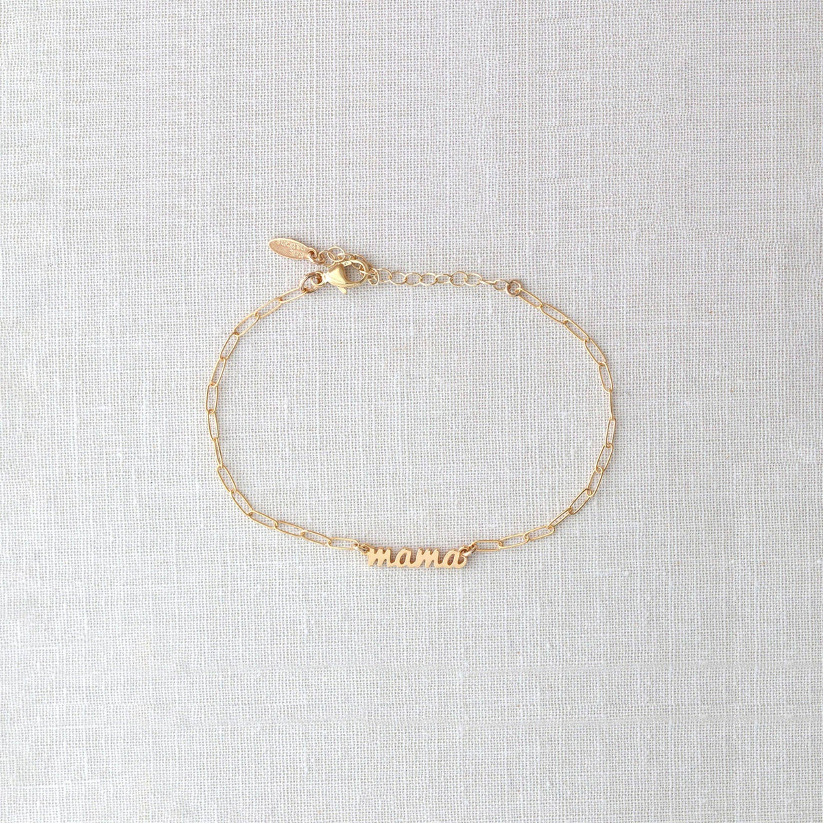 Gold bracelet with 'mama' engraving on a light gray background
