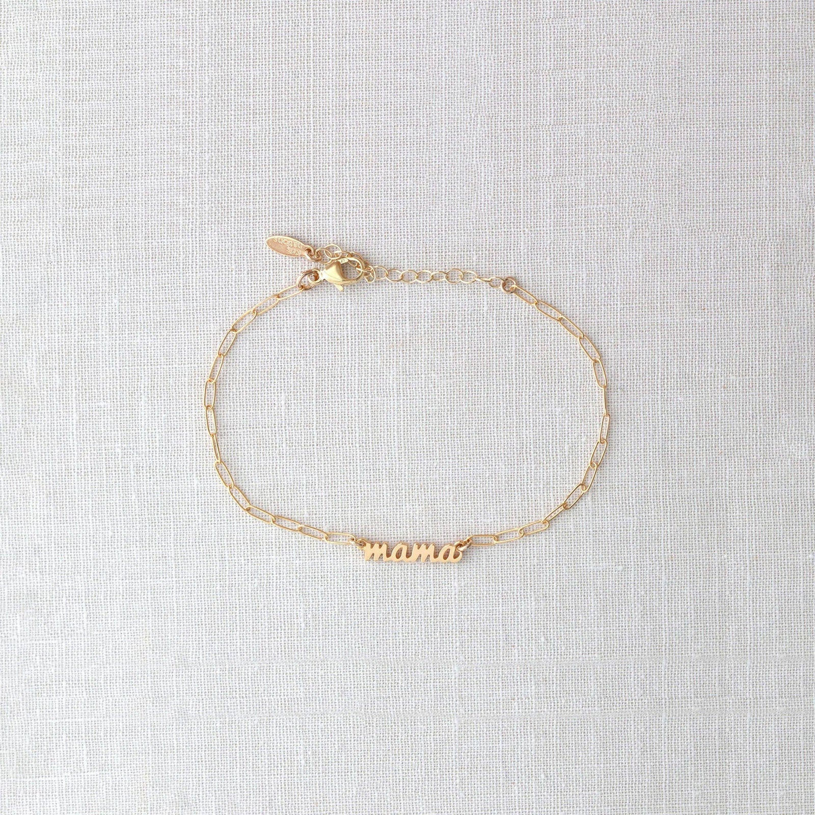 Gold bracelet with 'mama' engraving on a light gray background