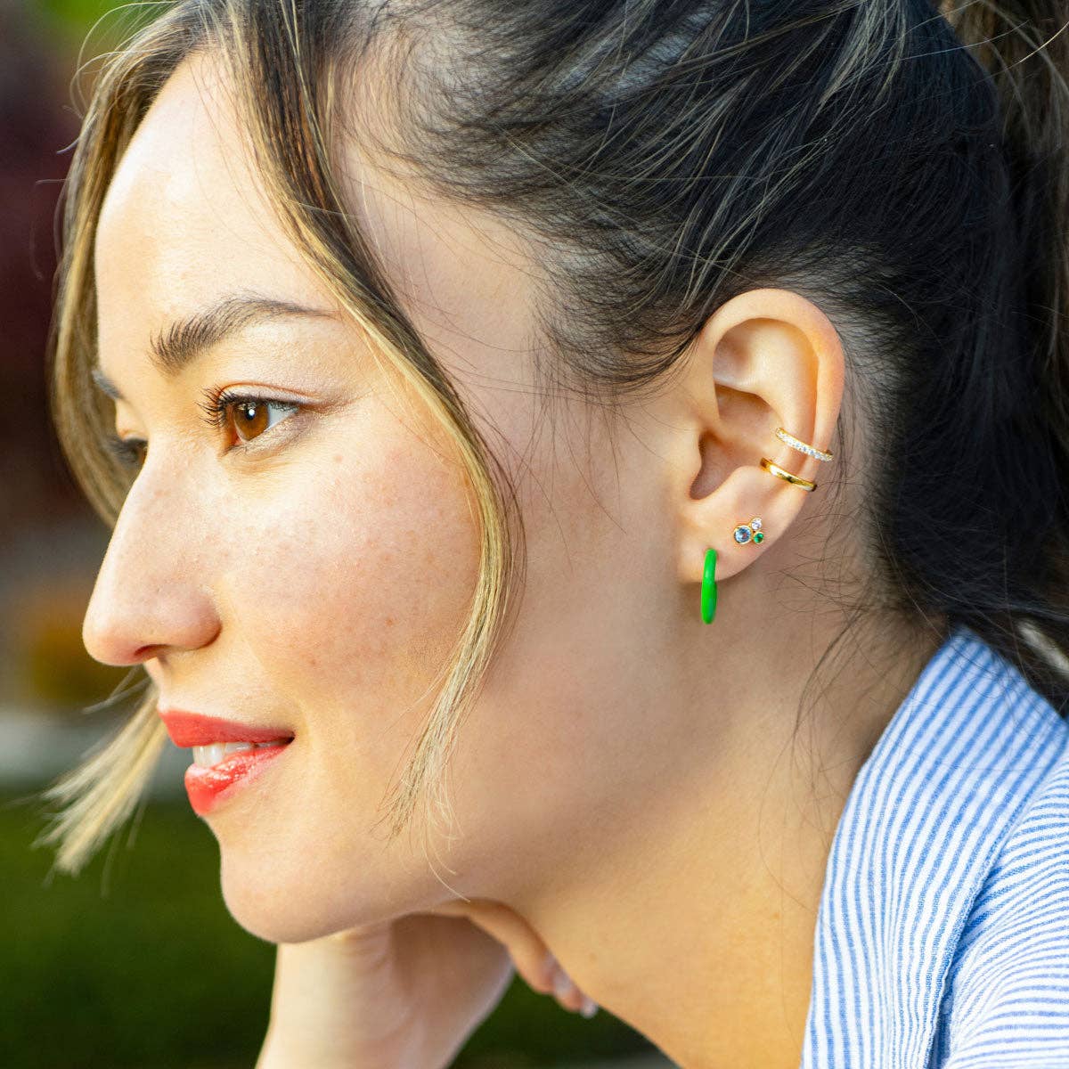 Close-up of a woman wearing multiple earrings outdoors