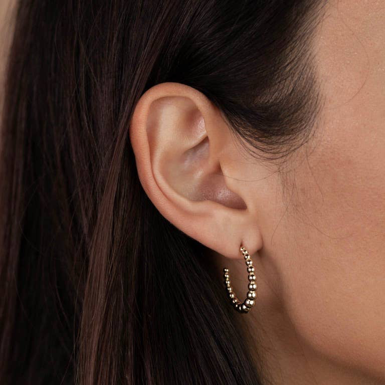 Gold hoop earrings on a Jaxkelly branded card with a beige background