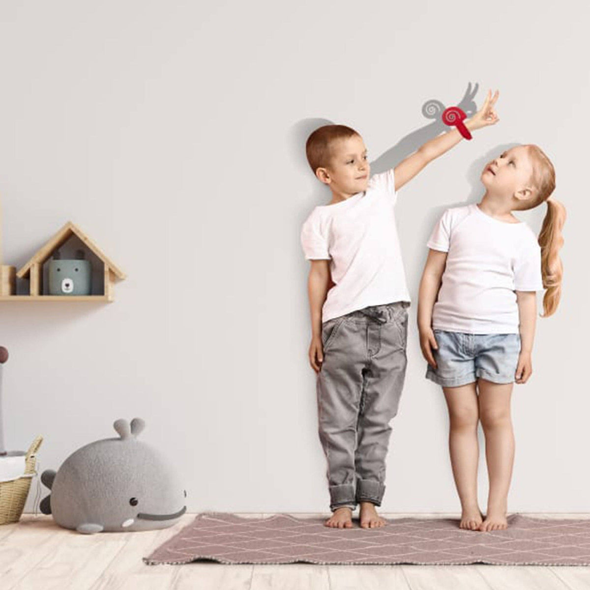 Two children standing on a rug in a room with toys and snail shadow puppet.