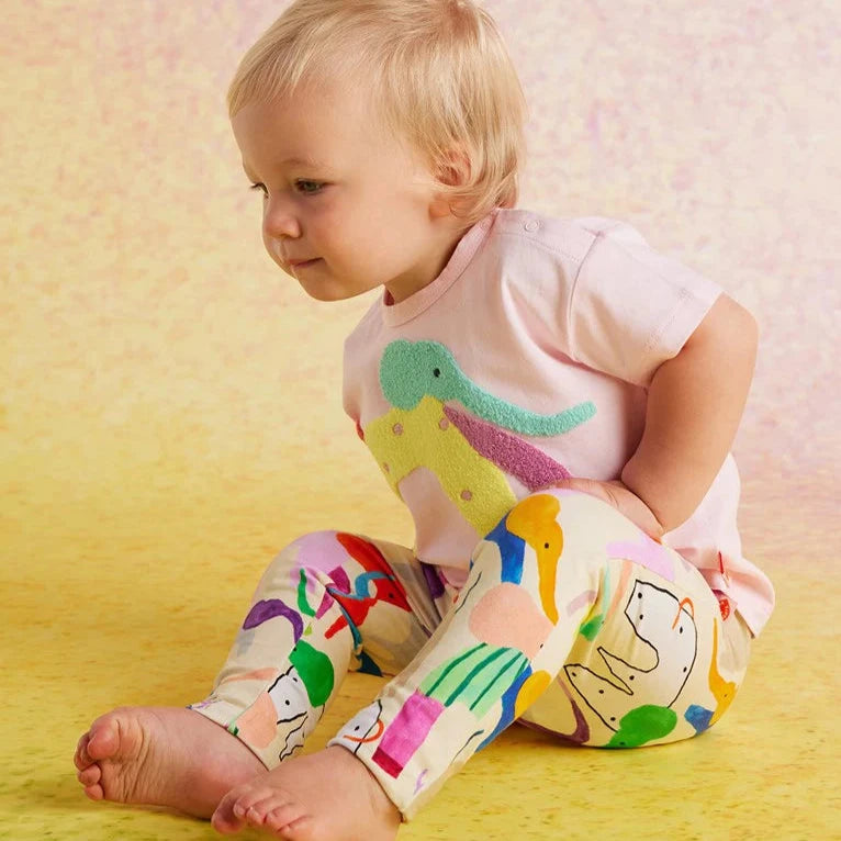Child wearing a colorful outfit with animal prints on a yellow background