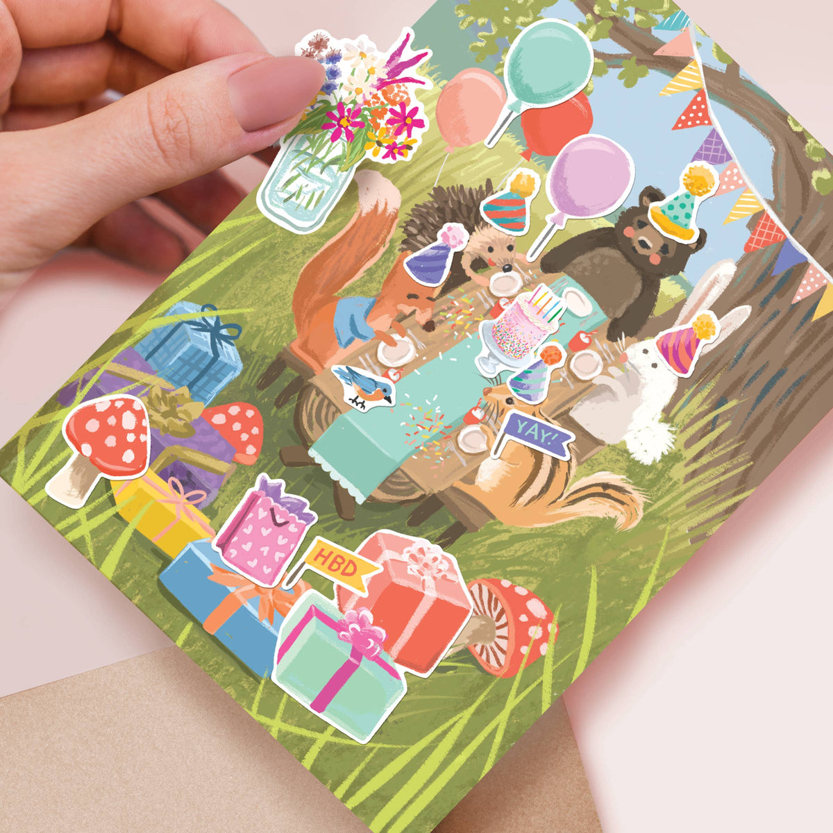 Hand holding a card with animal-themed stickers on a light pink background