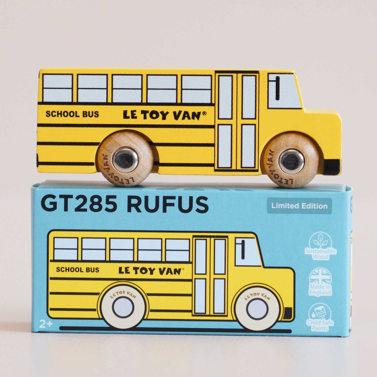Yellow toy school bus with 'Le Toy Van' branding on a matching box.