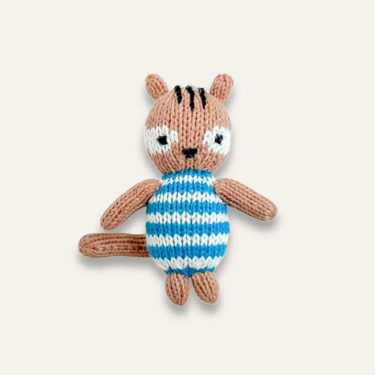 A hand-knitted plush toy of a small brown squirrel wearing a blue and white striped sweater, set against a solid light beige background.