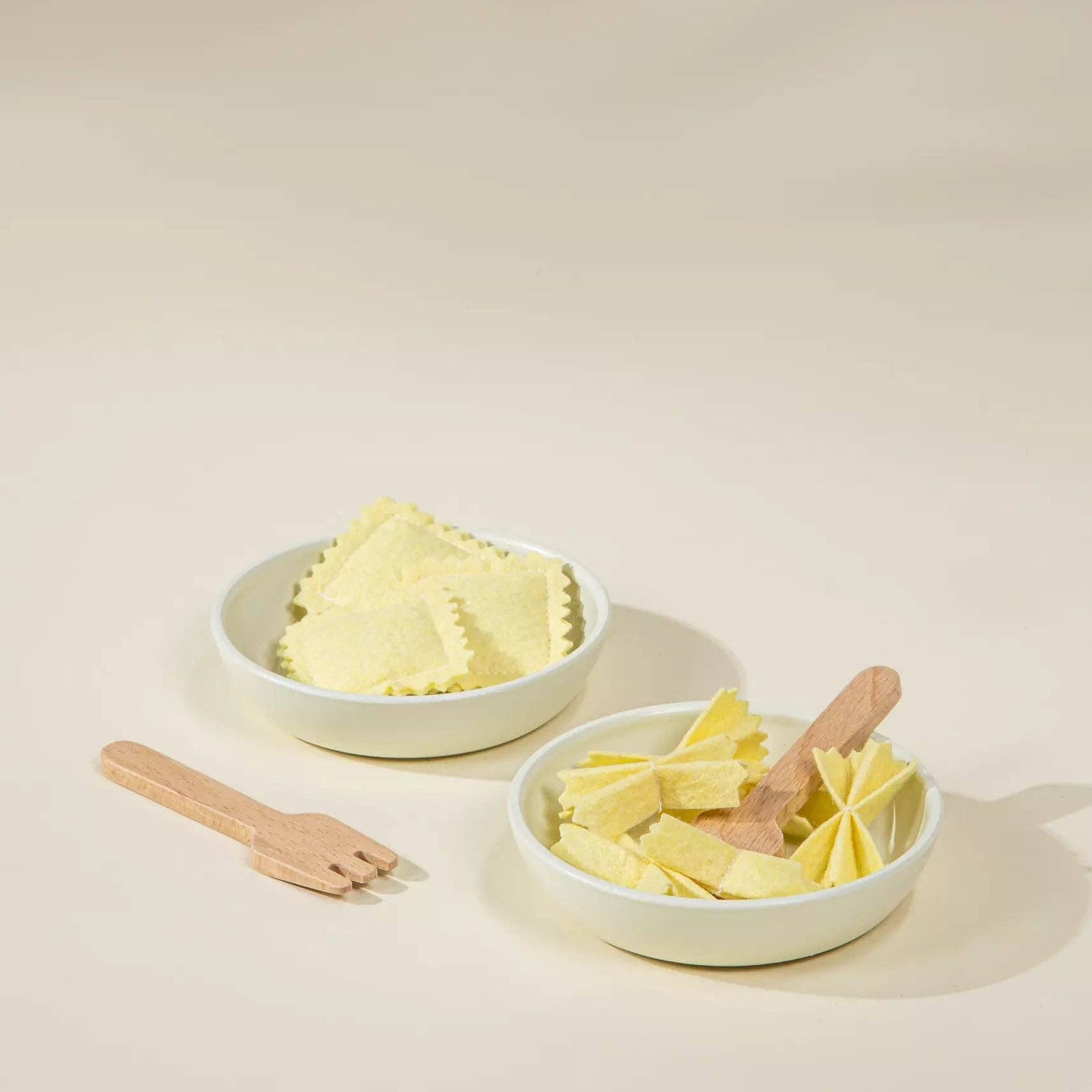 Set of white containers with pasta and wooden utensils on a light background