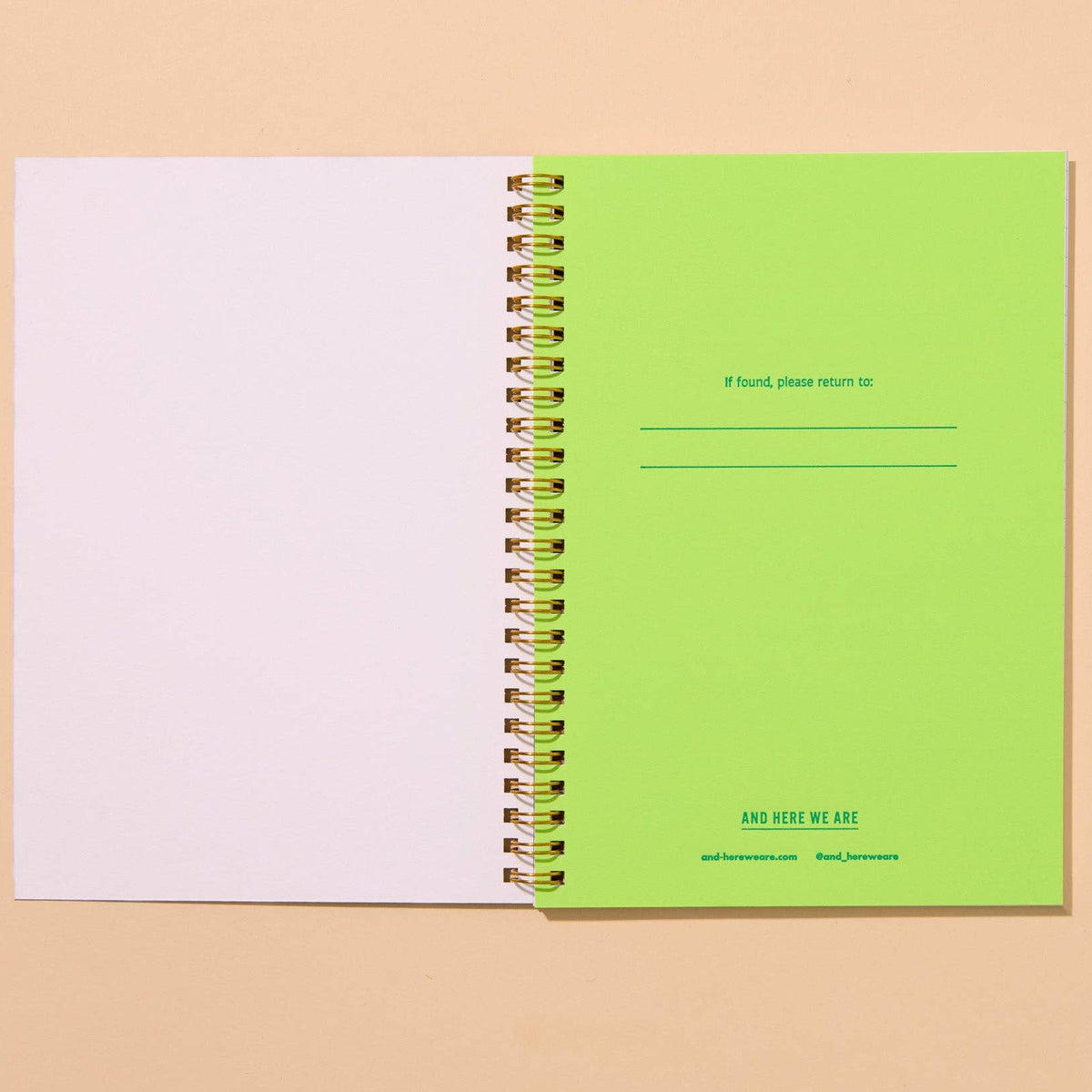 Open spiral-bound notebook with green and white pages on a beige background