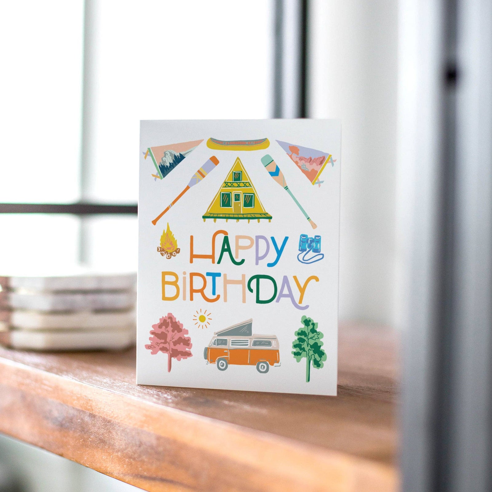 Birthday card with camping-themed illustrations and 'Happy Birthday' text.