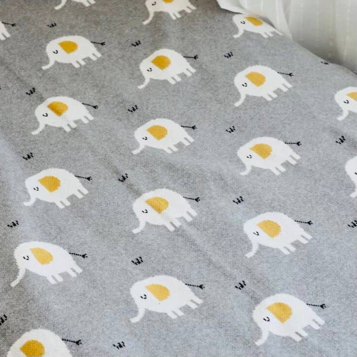 Gray blanket with elephant pattern on a bed