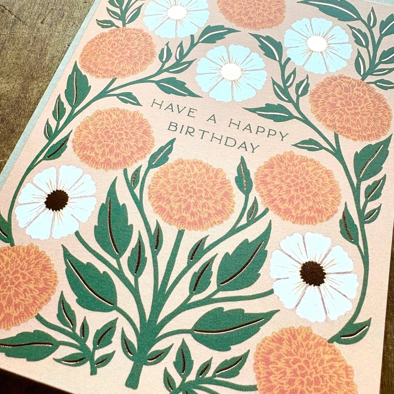 Floral birthday card with peach and white flowers on a wooden surface