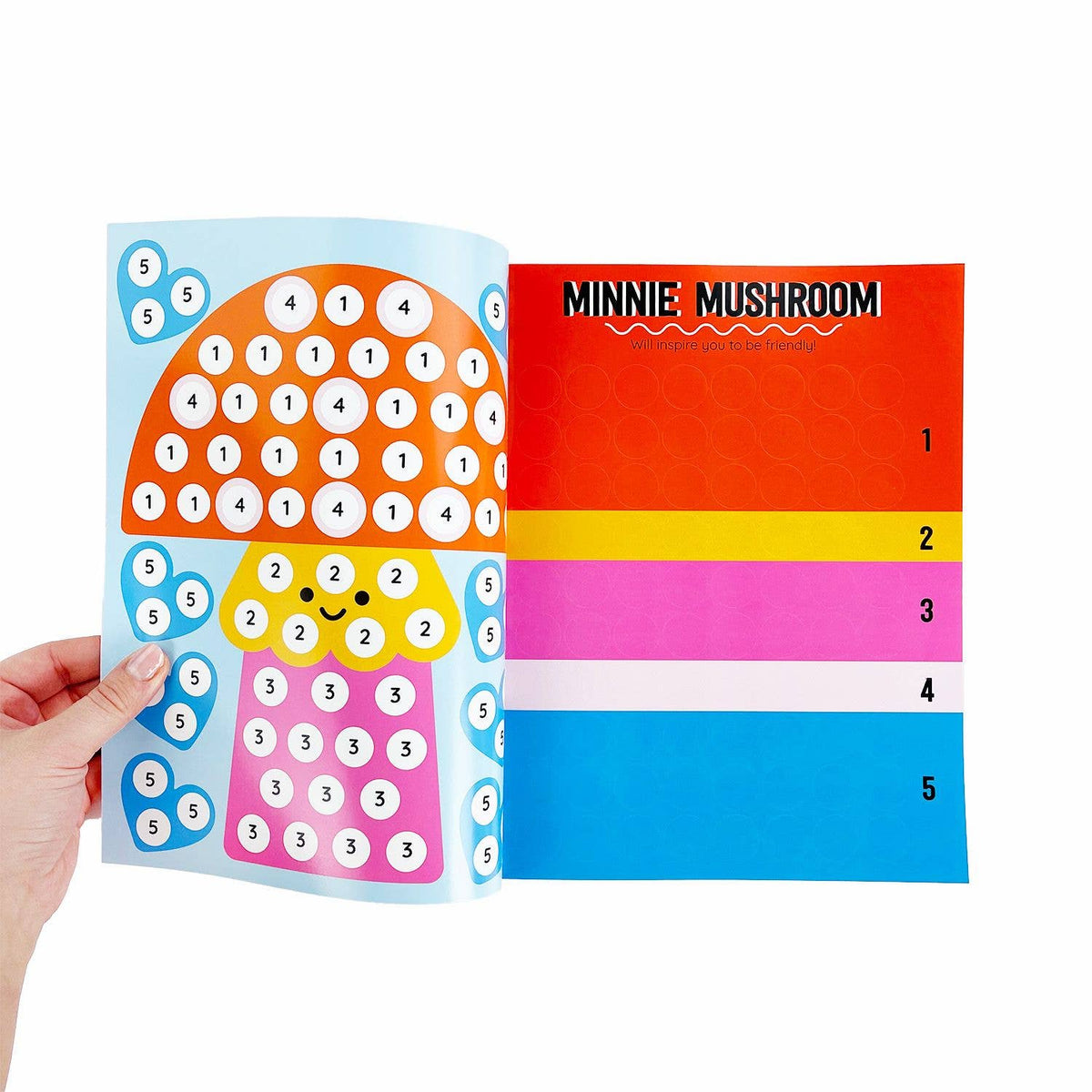 Colorful children's activity book with a mushroom design held by a hand on a white background