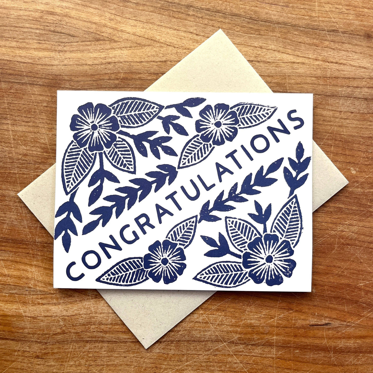 Greeting card with floral design and 'Congratulations' text on a wooden surface