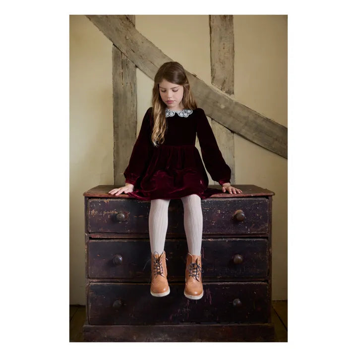 Young girl sitting on a wooden dresser with rustic wall background