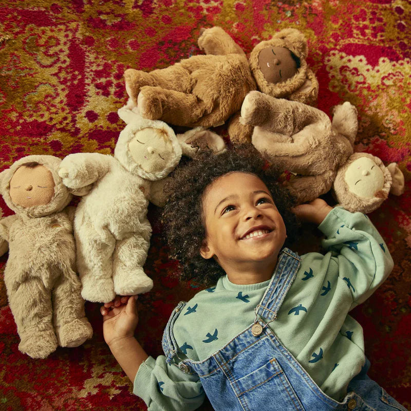 Stuffed toy resembling a baby in a brown outfit on a soft white surface