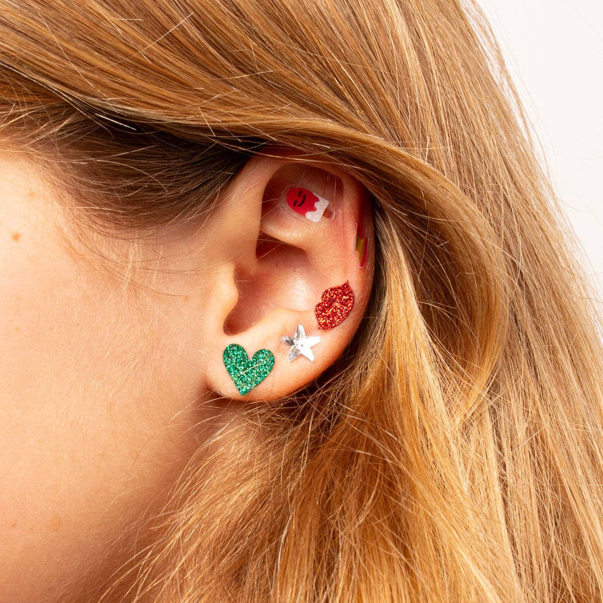 Close-up of an ear wearing colorful earrings with a blurred background
