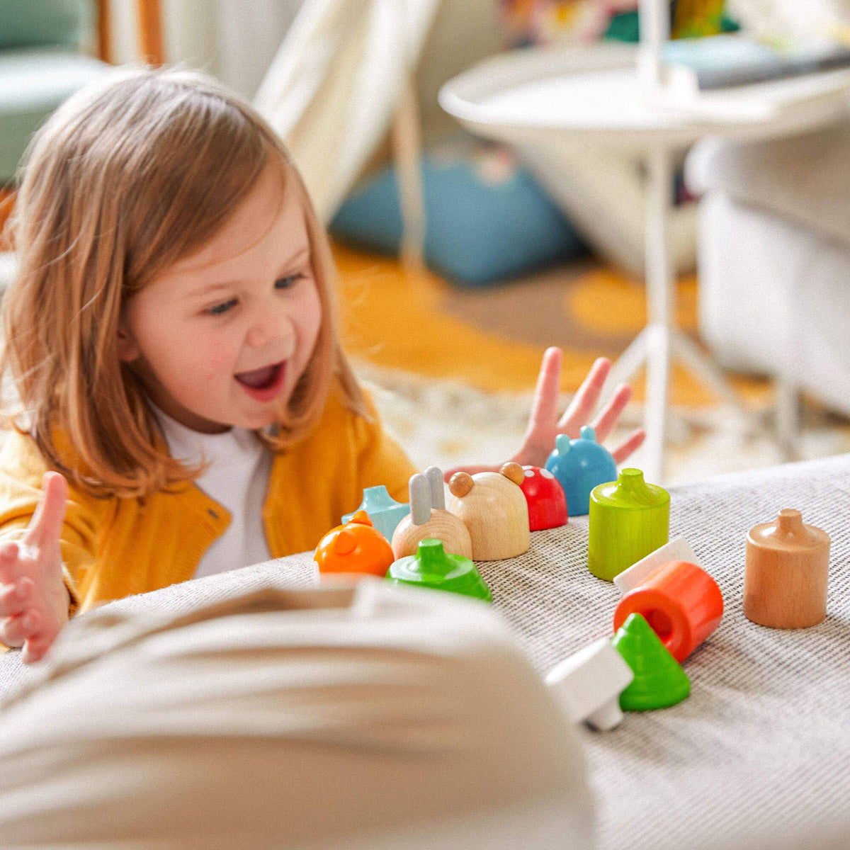 Child playing with colorful wooden toys on a blanket