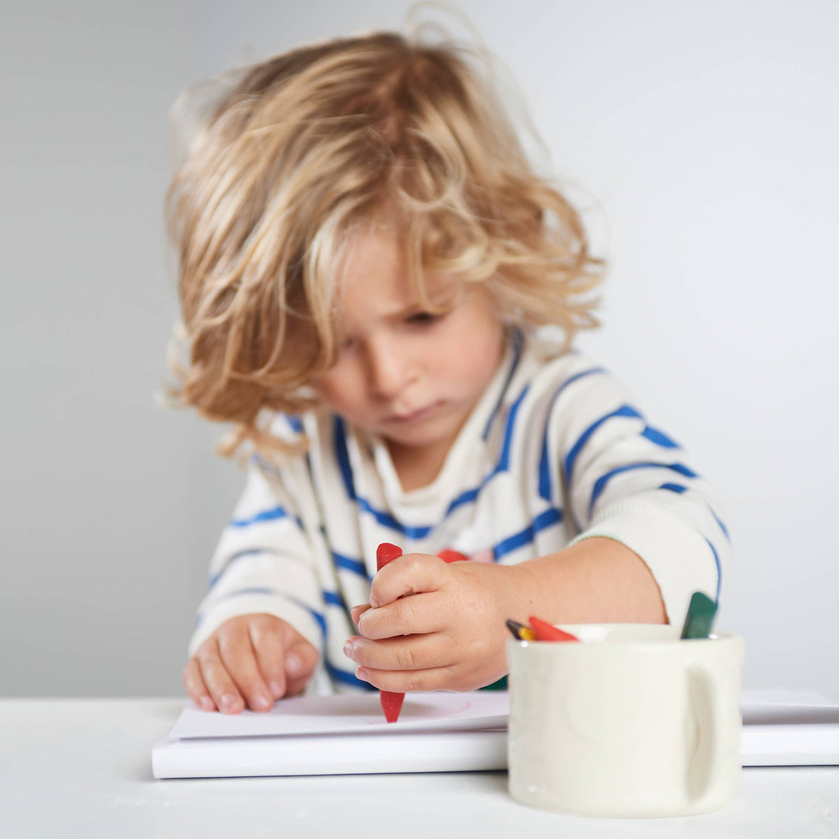Child drawing with colorful markers on a white surface