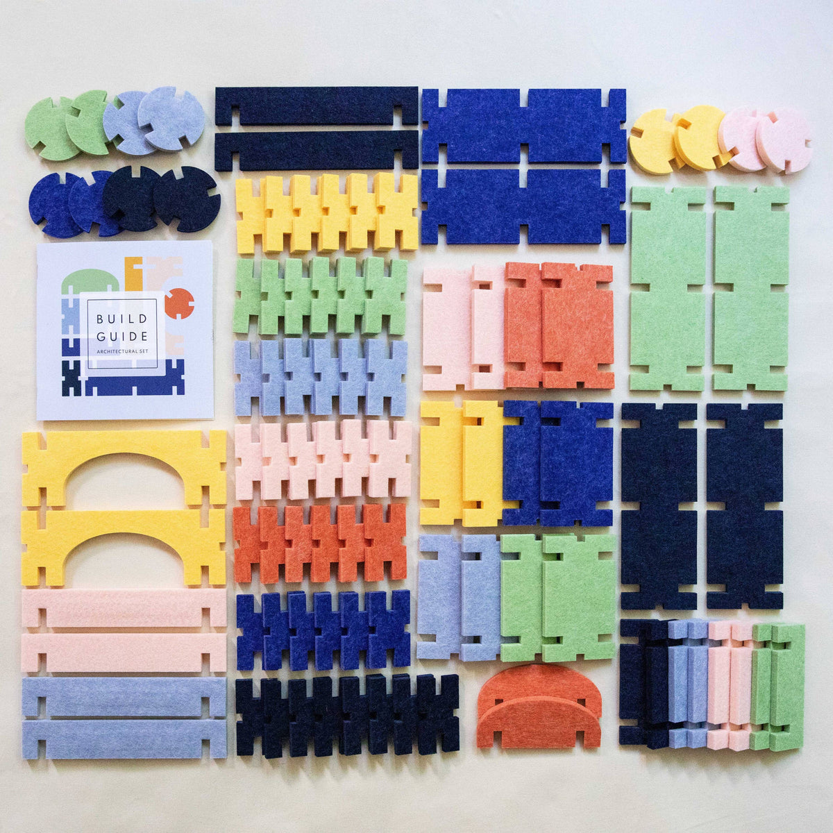 Colorful felt interlocking pieces on a white background with a small book titled &#39;Build Guide&#39;.
