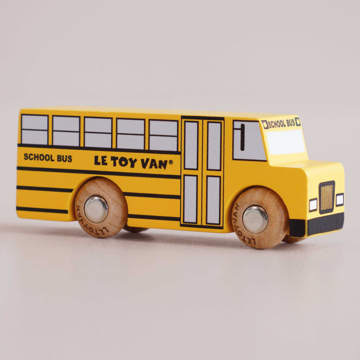 Yellow toy school bus with 'Le Toy Van' branding on a light gray background