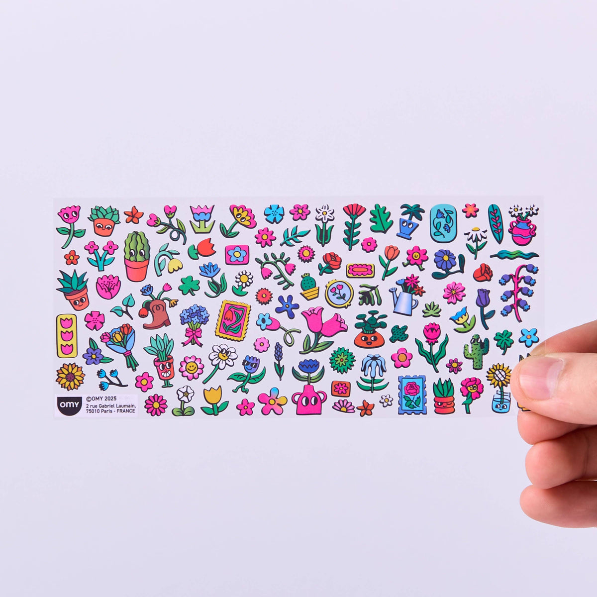 Collection of colorful stickers on a white card held by a hand against a light background