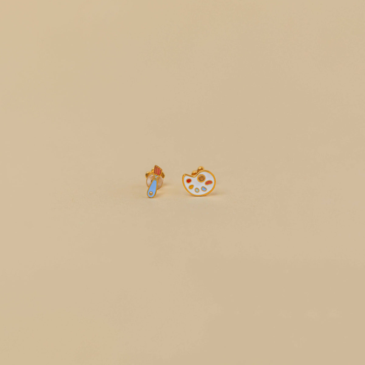 Two small earrings on a beige background