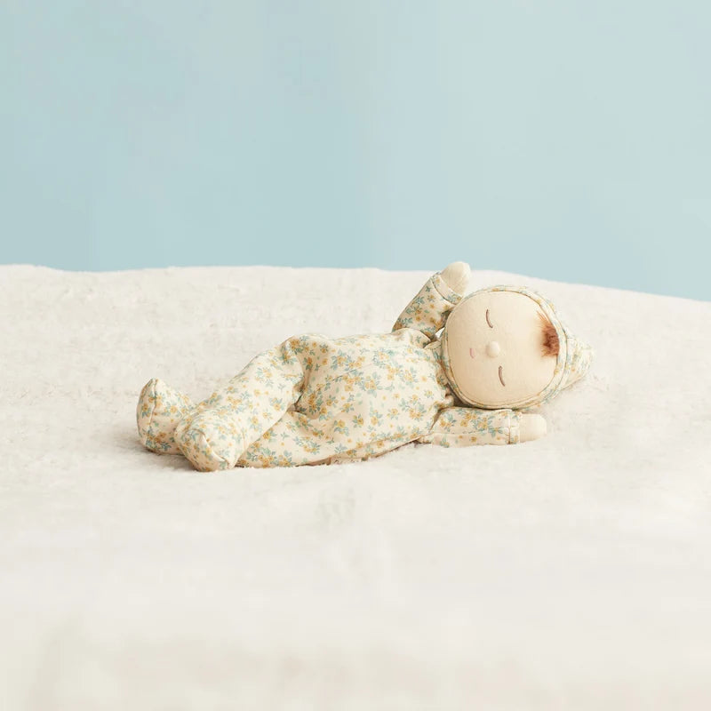 A fabric doll with a floral print onesie, cream-colored face and hands, and short red yarn hair, shown against a plain white background.