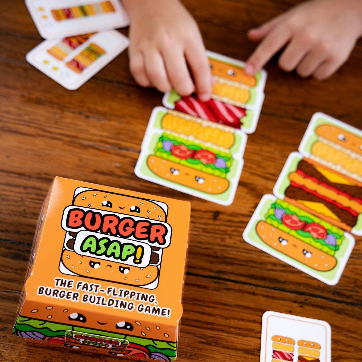 Burger building game with cards and box on a wooden surface