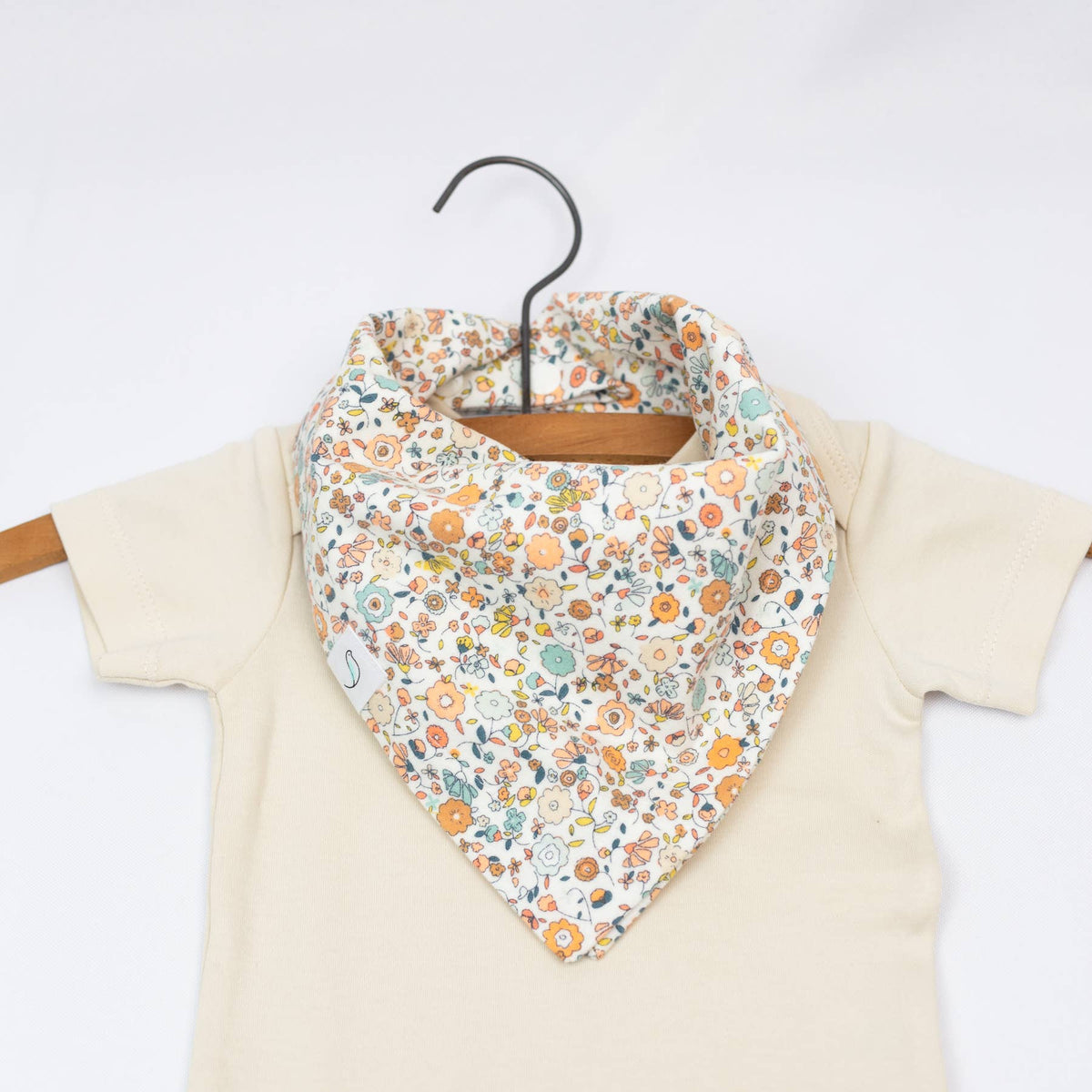 Floral patterned baby bib on a hanger with a white background
