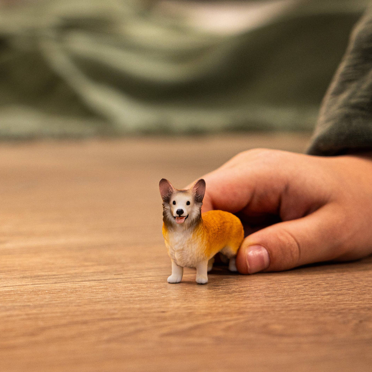 Small dog figurine held by a hand on a wooden surface