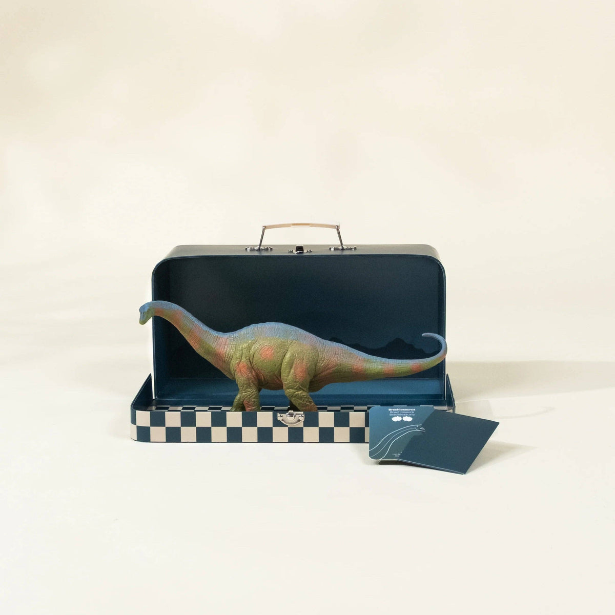 Dinosaur toy in a suitcase with a passport on a beige background