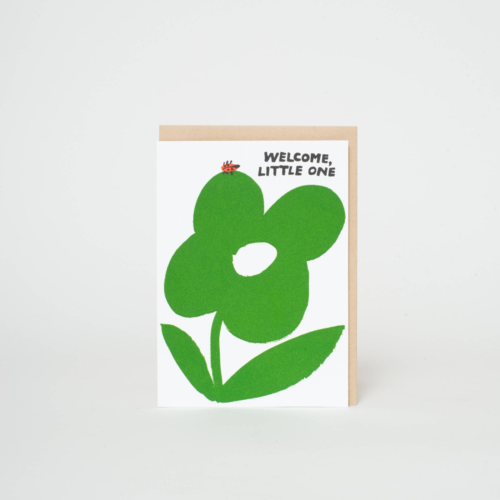 A greeting card with a green floral design and the text 'WELCOME, LITTLE ONE' on it.