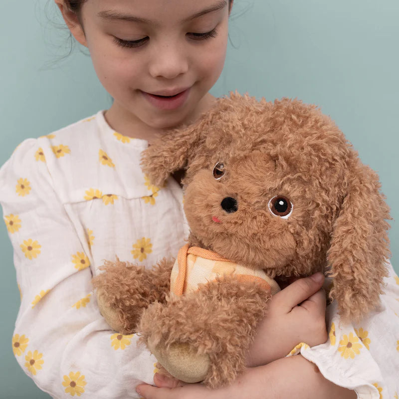 Child holding a plush dog with dog toy with a blurred green background