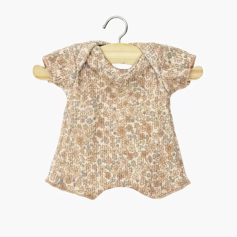Baby doll romper with floral pattern on a wooden hanger against a white background