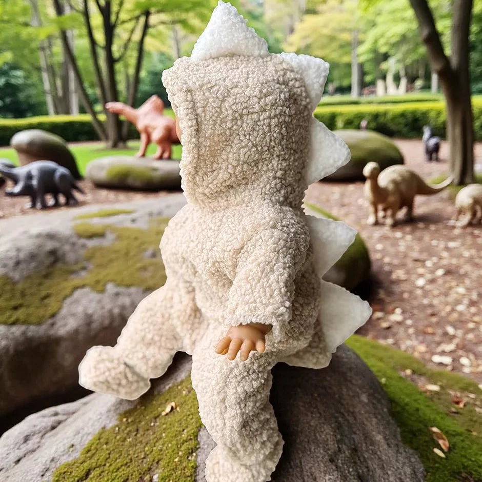 Stuffed dinosaur doll on a rock with a park setting in the background