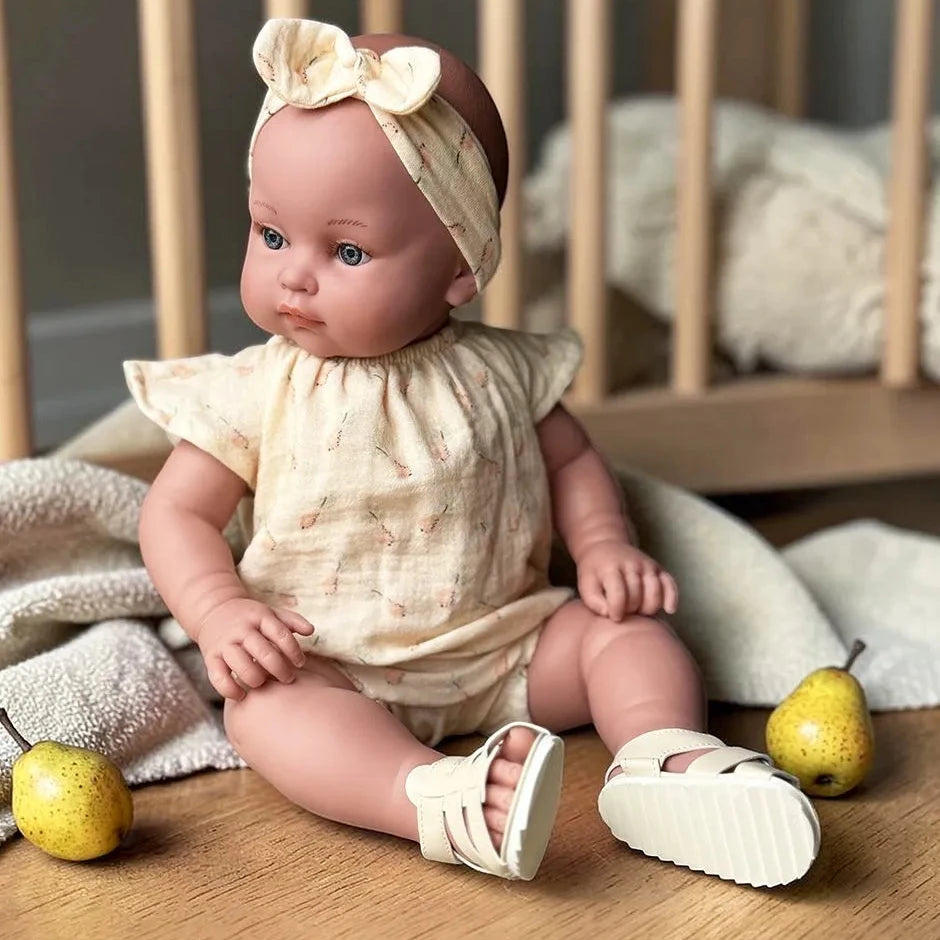 Baby doll in a crib with pears on a wooden floor