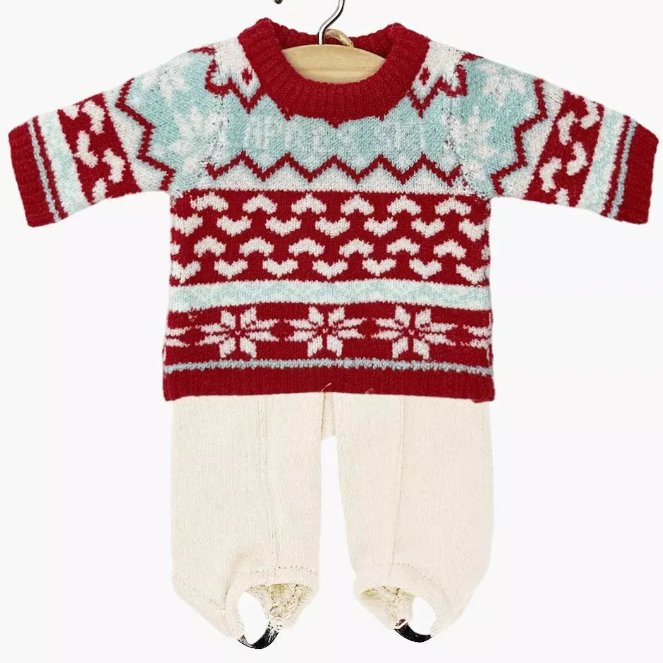 Baby doll outfit with red and white patterned sweater and white pants on a hanger against a white background