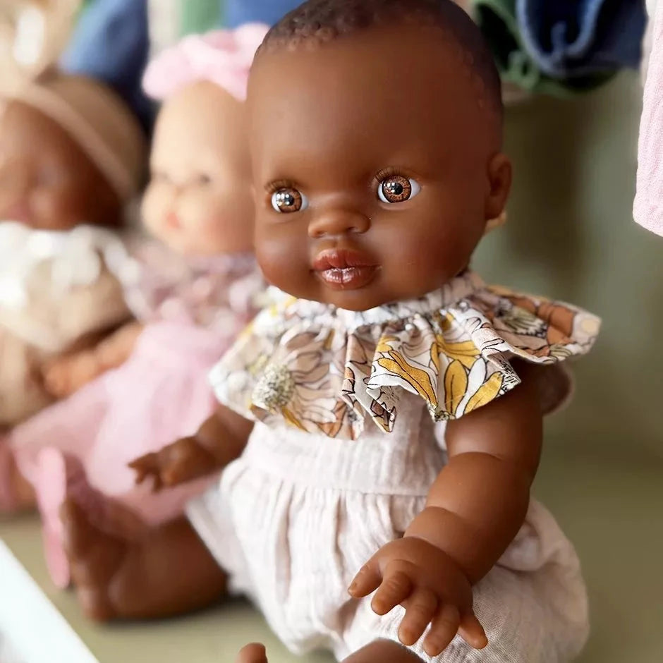 Baby doll with a floral outfit sitting among other dolls.