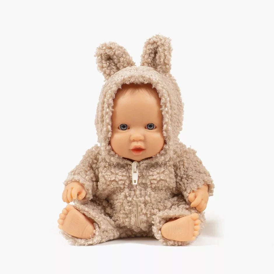 Baby doll wearing a beige bunny onesie on a white background